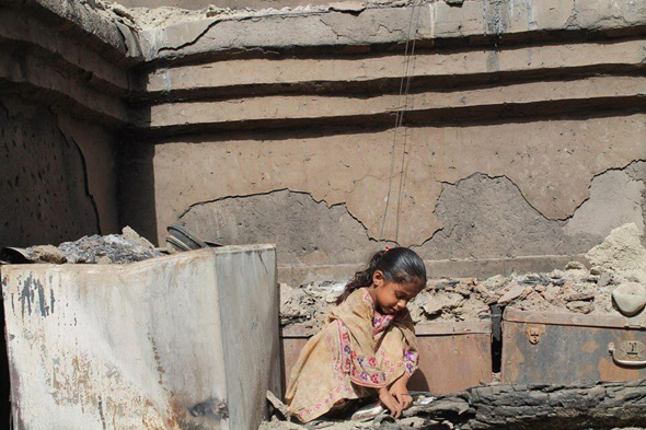 Young Baloch girl searches for books in burned rubble of her house